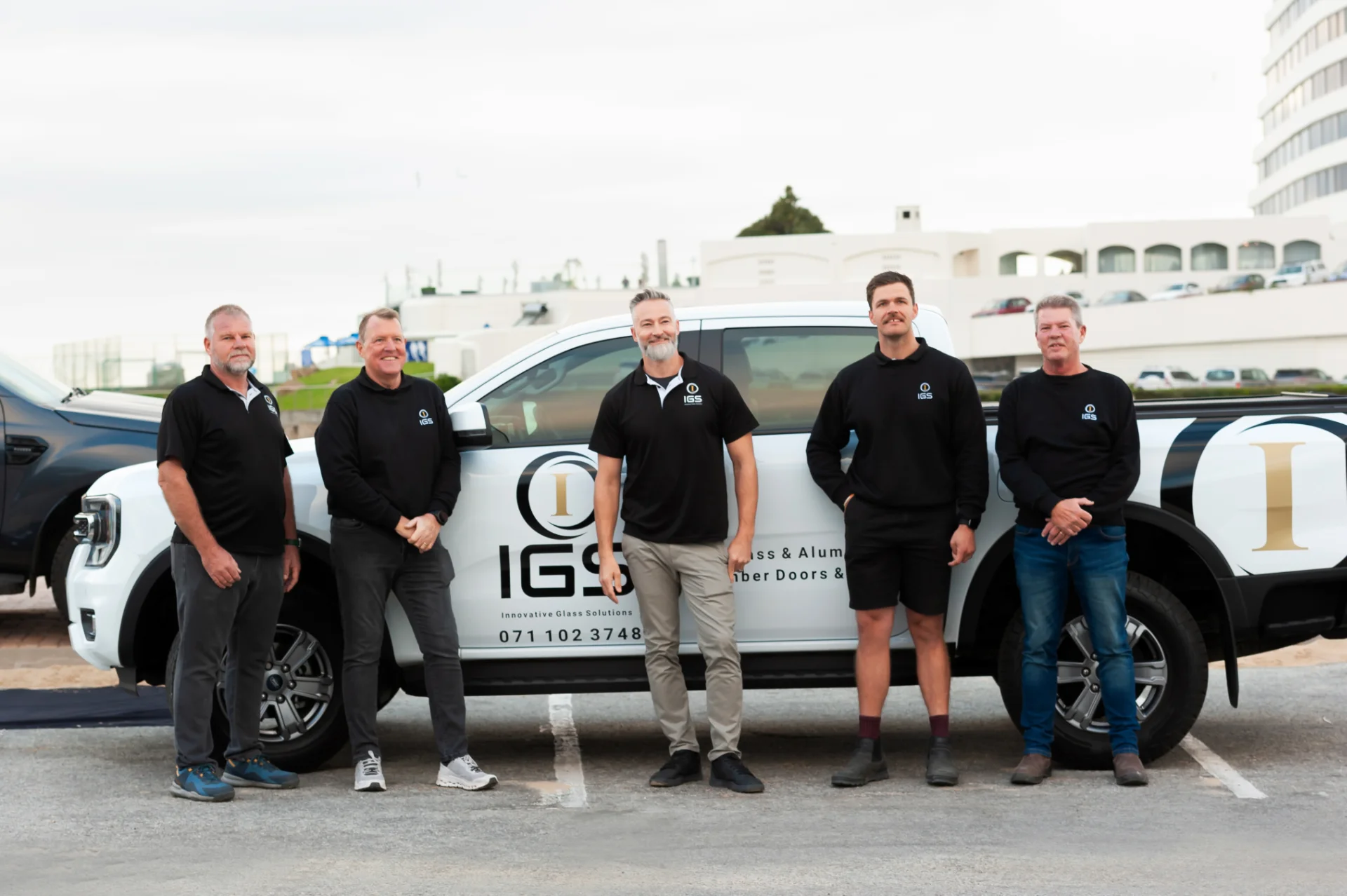The IGS team standing together in front of a branded company vehicle
